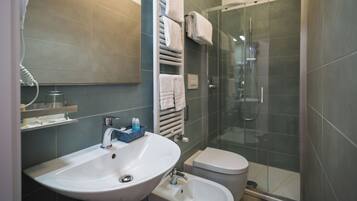 Un baño moderno con lavamanos, inodoro y ducha con mampara de vidrio.