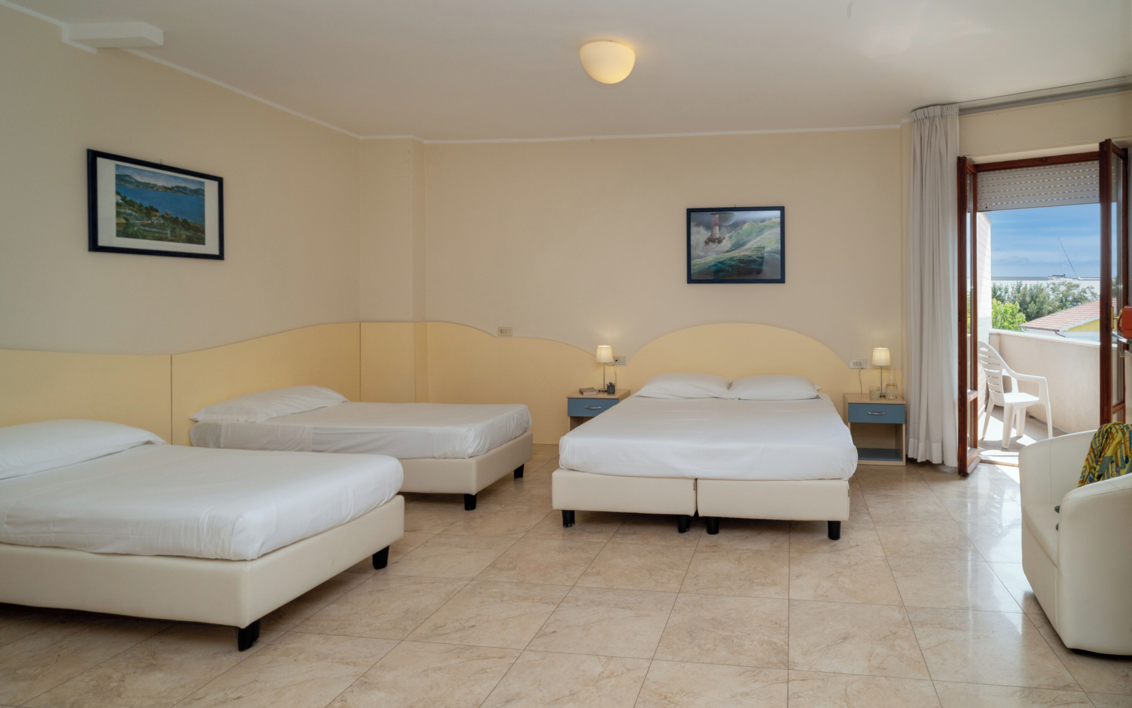 Quarto de hotel com três camas, varanda e uma vista, além de um quadro na parede.