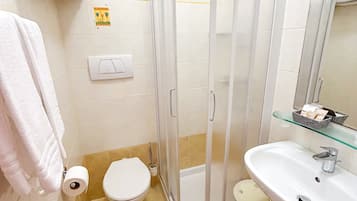 A bathroom with a glass shower enclosure, a toilet, a sink, and a towel rack.