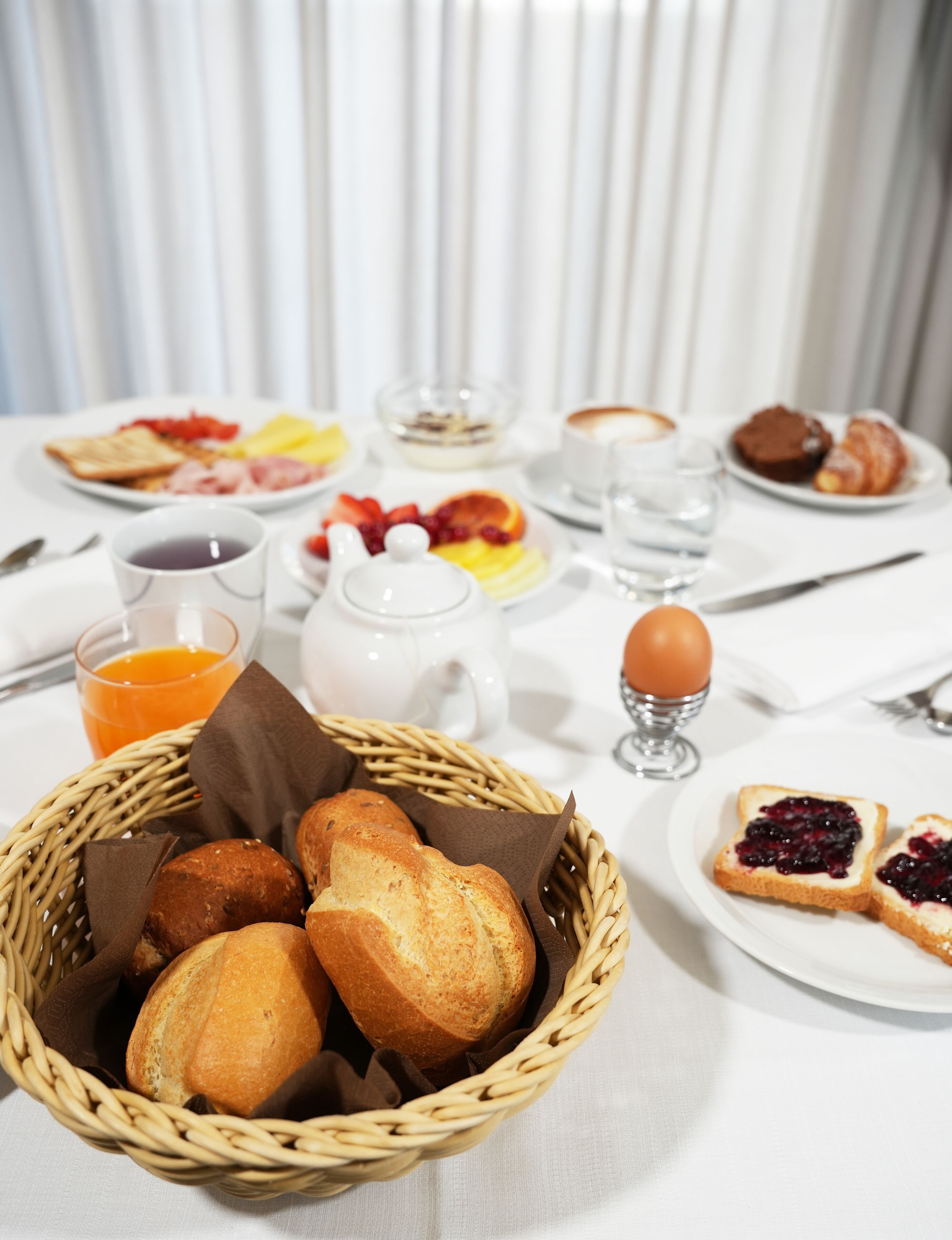 Una mesa de desayuno con diversas comidas, como pan, bollería y fruta.