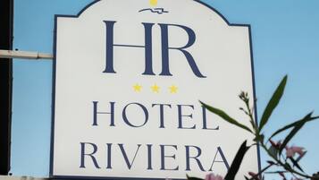 A sign for HR Hotel Riviera with a clear sky in the background.