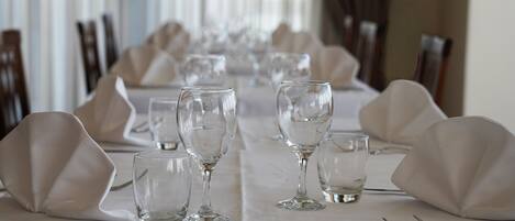 A dining table set with white tablecloths, clear glassware, and folded napkins.