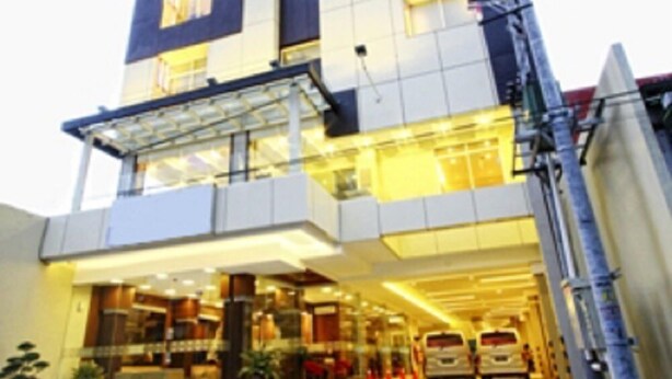 Un edificio moderno con facciata in vetro, diversi piani e un'area di parcheggio antistante.