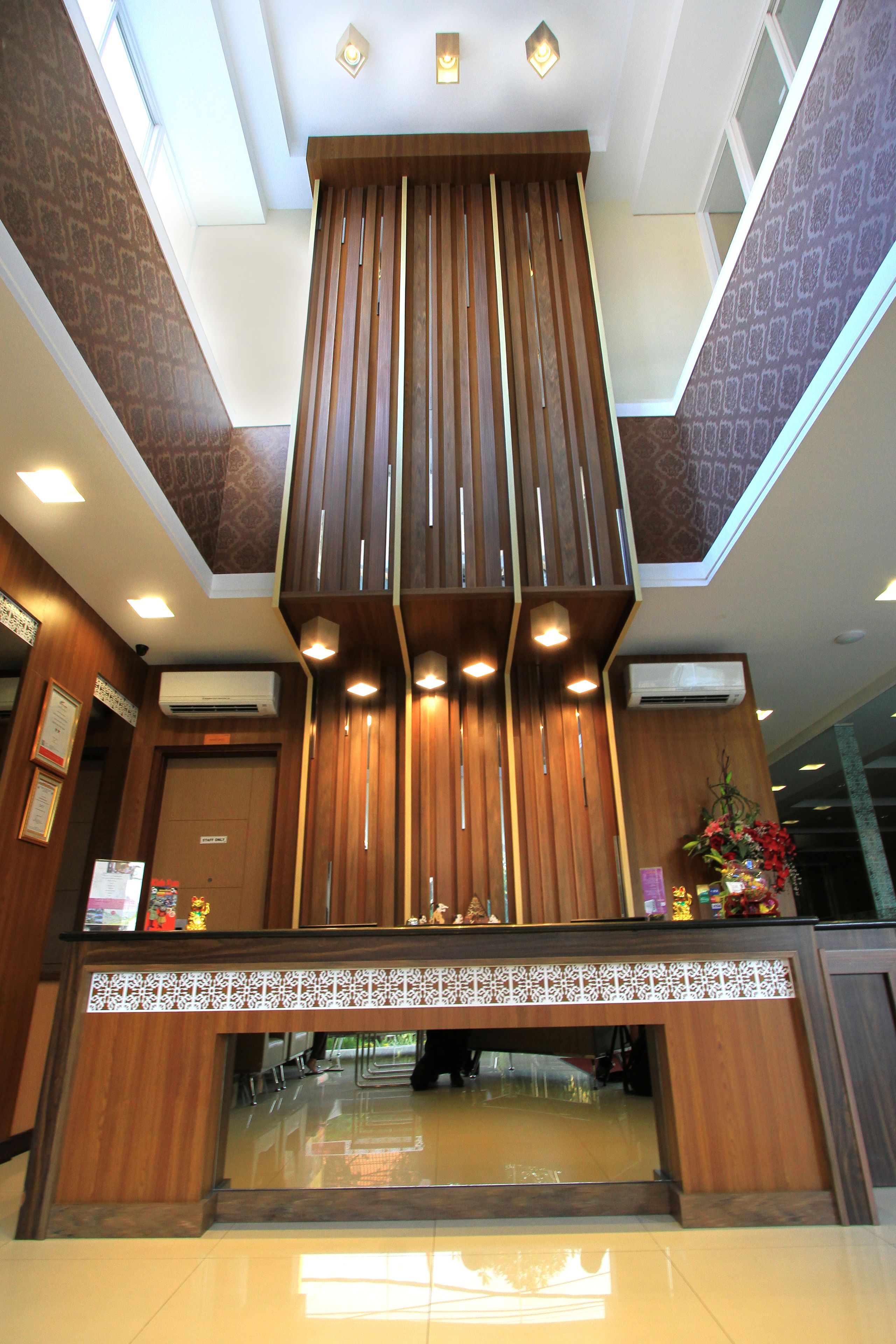 A reception desk with a wooden finish, air conditioning units, and a decorative floral arrangement.