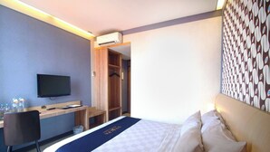 Una camera d'albergo con un letto, una scrivania, una televisione e un armadio.