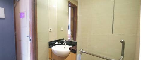 A bathroom with a sink, mirror, and a shower area.