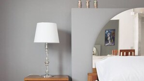 A bedroom with a wooden nightstand, a white lamp, a bed with white bedding, and a mirror above the bed. - Triple Tree Resort (Lam Luk Ka)