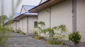 A row of single-story buildings with a uniform architectural style, featuring a flat roof and a simple facade. - Triple Tree Resort (Lam Luk Ka)