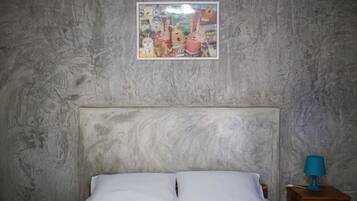 A bedroom with a bed, a nightstand with a lamp, and a wall with a framed picture.
