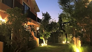 A residential building with a paved pathway leading to a gated entrance, surrounded by trees and potted plants. - Sata House Buoutique Resort (Nakhon Ratchasima)