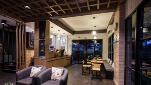 A modern interior with a bar area, seating, and large windows. - Sata House Buoutique Resort (Nakhon Ratchasima)