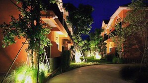 A residential building with a curved driveway, surrounded by trees and illuminated by artificial lighting. - Sata House Buoutique Resort (Nakhon Ratchasima)