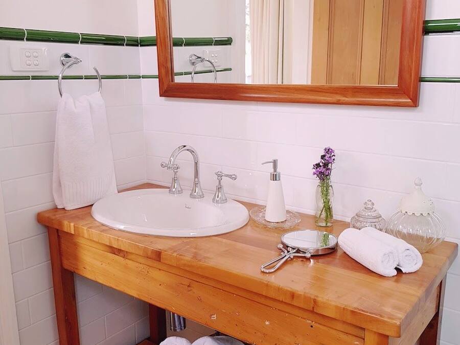 Un baño con tocador de madera, dos lavamanos, un espejo y una cesta de toallas.