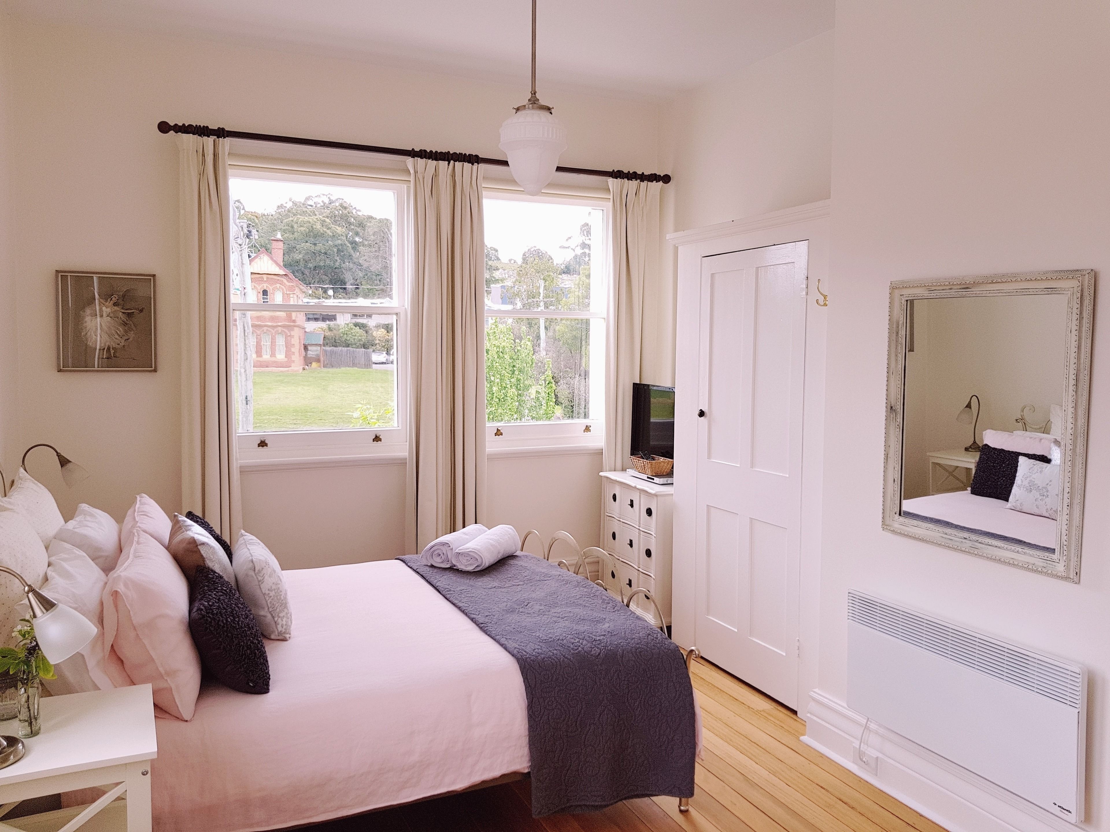 A bedroom with a bed, a dresser, a mirror, and a radiator.
