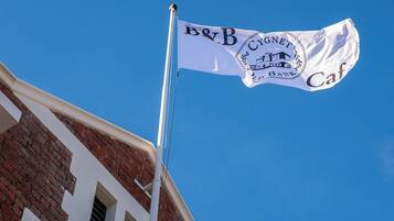 A flag with 'B&B Cygnet Hotel Bank Cafe' text and a building with a brick facade.