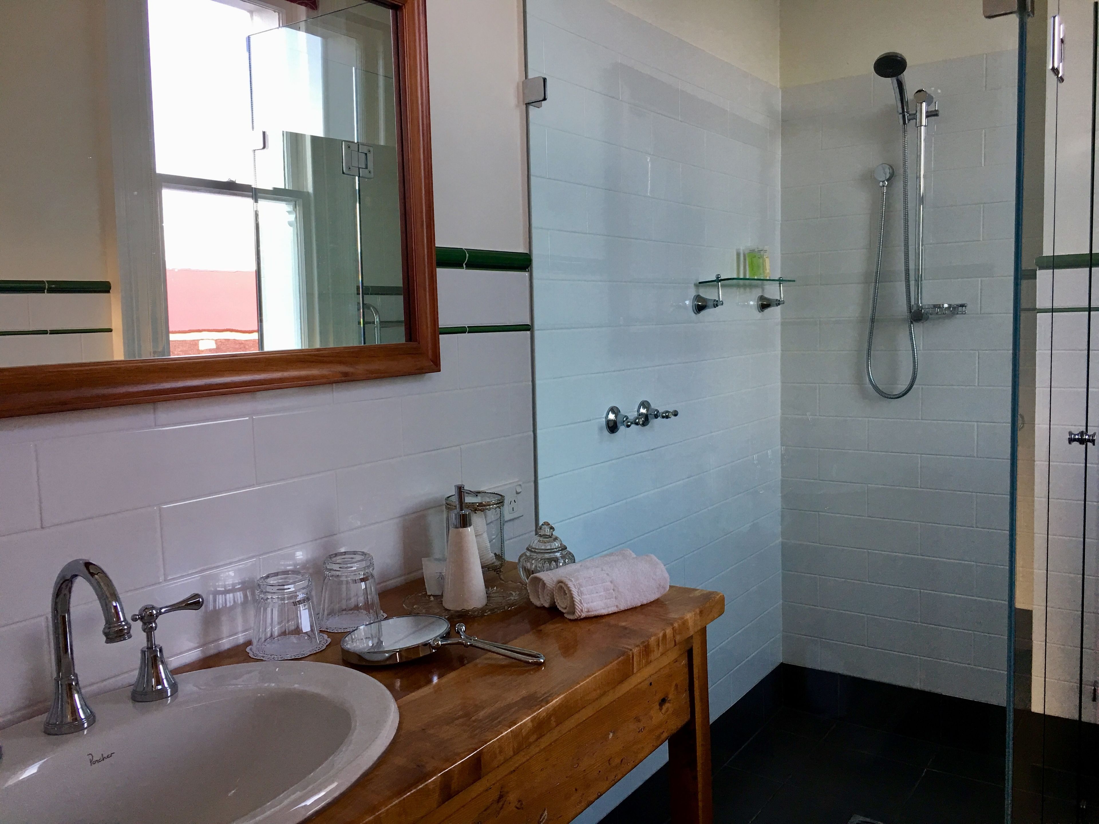 A bathroom with a sink, mirror, and shower.
