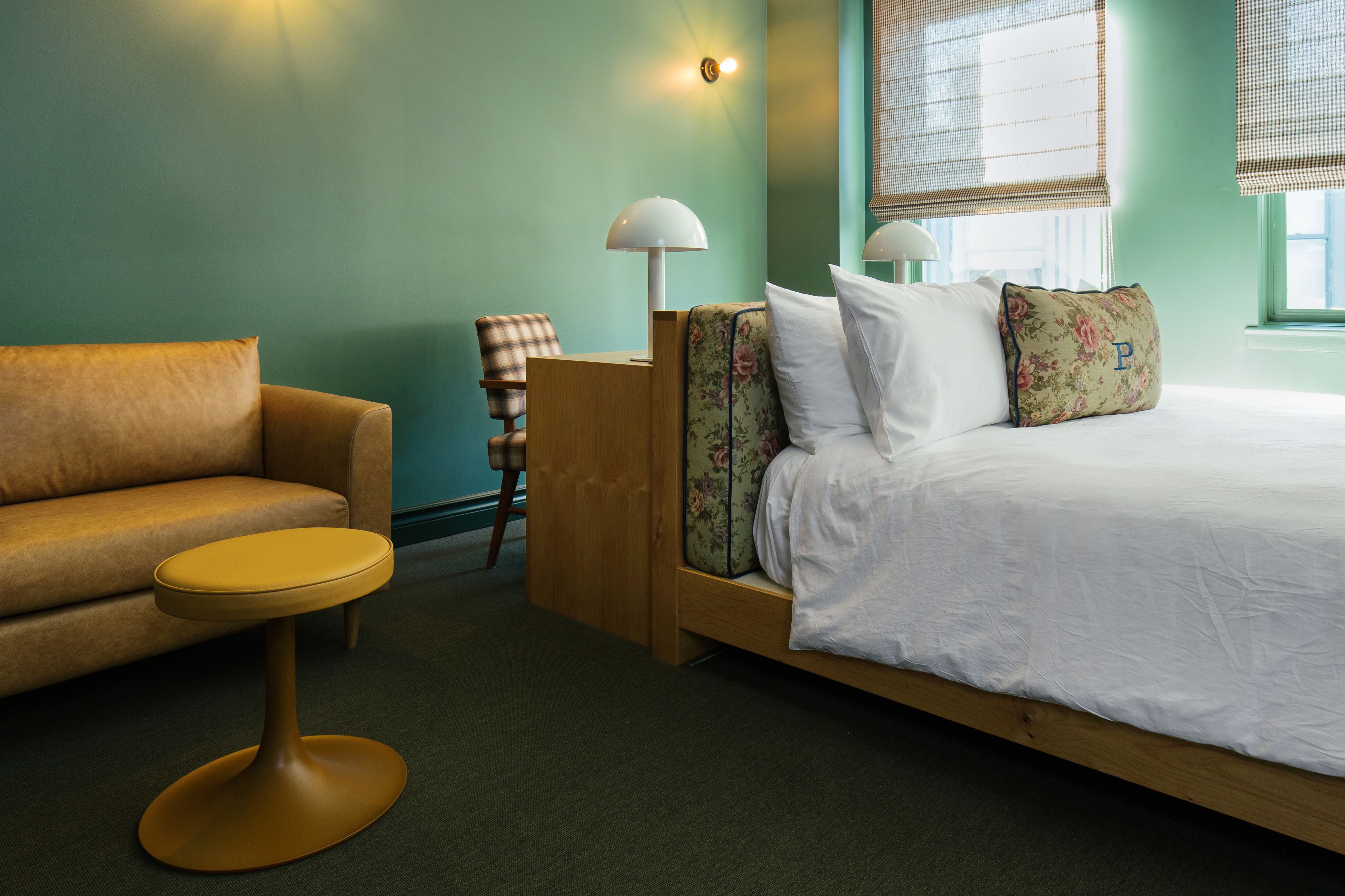 A bedroom with a bed, a sofa, a small round table, and a chair.