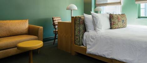 A bedroom with a bed, a sofa, a small round table, and a chair.