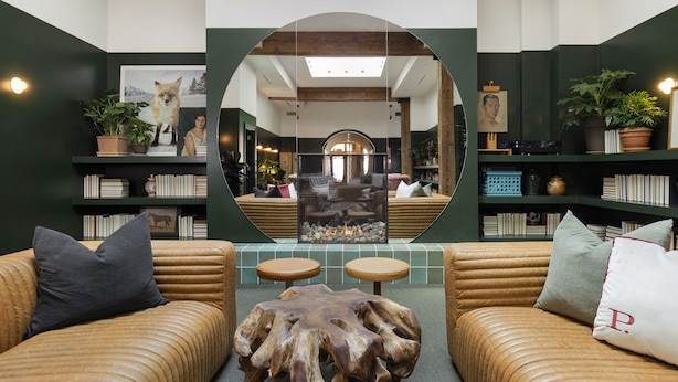 Un espace salon accueillant, avec deux canapés en cuir, une table basse en bois et un grand miroir qui agrandit visuellement l’espace.