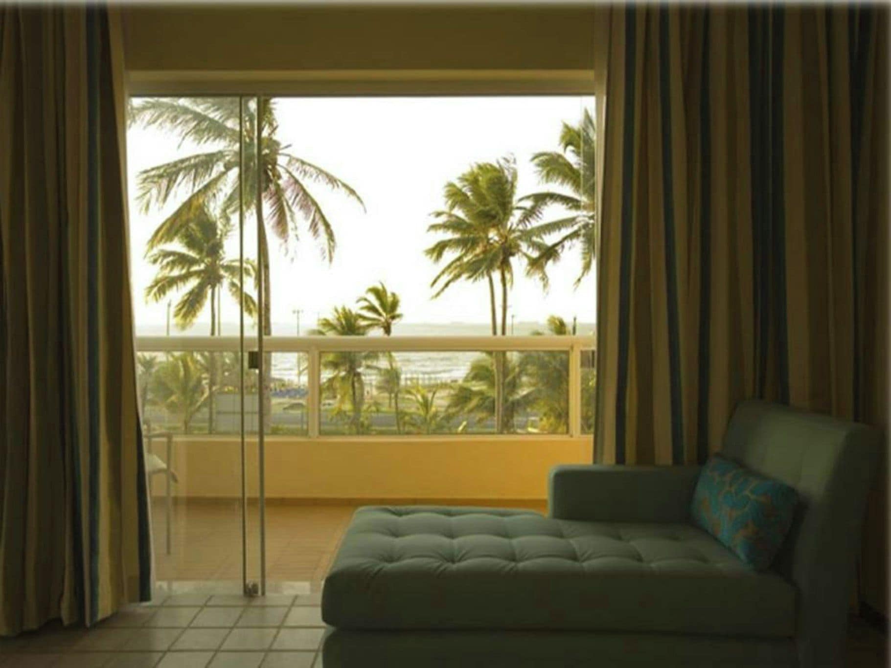Una habitación con sofá y vistas a palmeras y al océano.