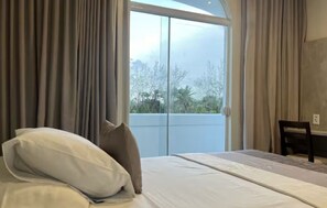 A bedroom with a large bed, a chair, and a view through a glass door to the outdoors. - Blue Tree Towers Sao Luis (São Luís)