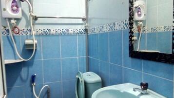 A bathroom with blue tiles, a sink, a mirror, and a toilet.