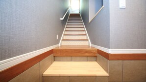Eine Treppe mit Holzsitzen und Handlauf, die zu einer Zwischenebene mit Lichtschalter führt.