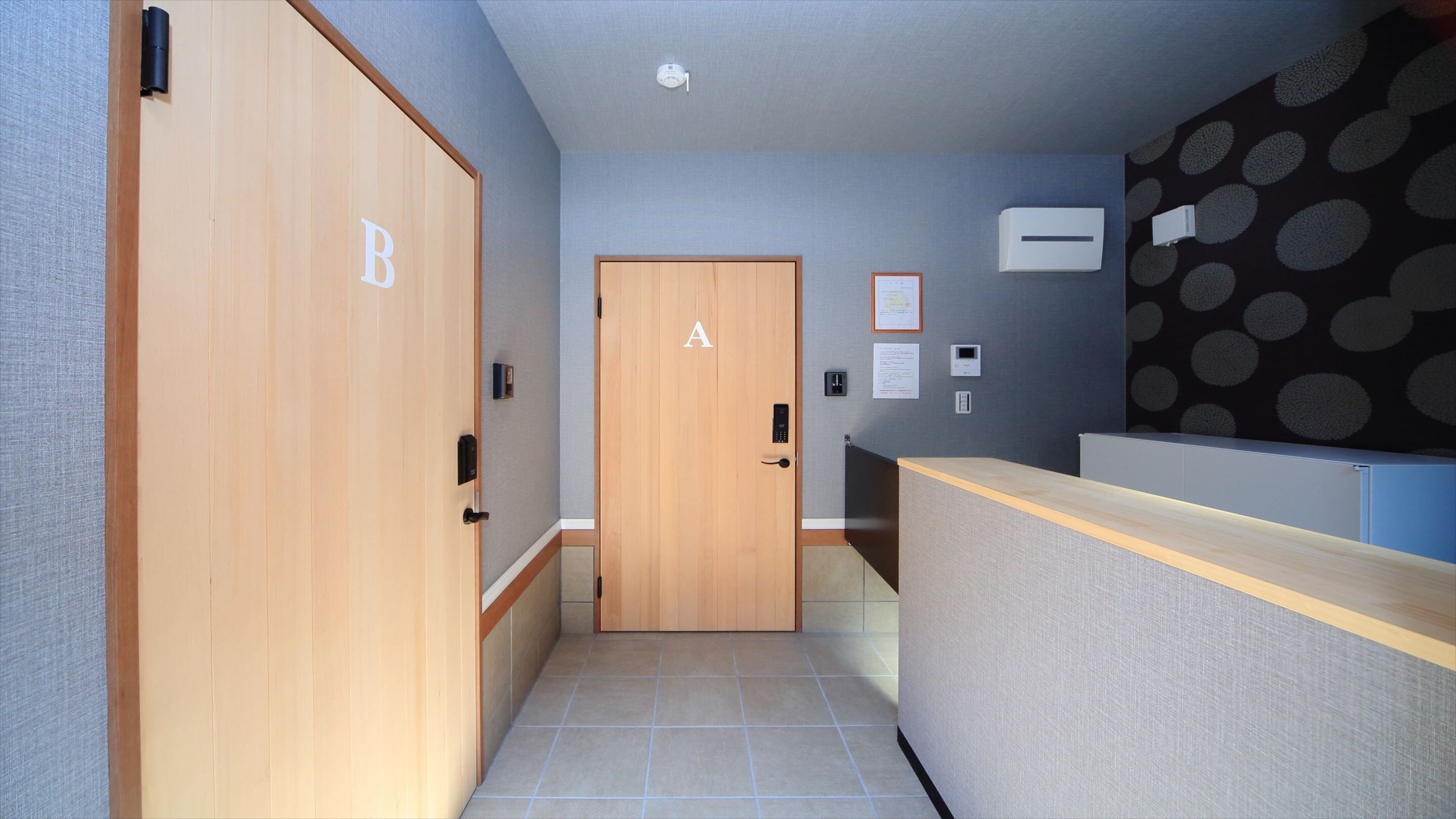 A hallway with a wooden door marked 'A', a reception desk, and a wall-mounted air conditioning unit.