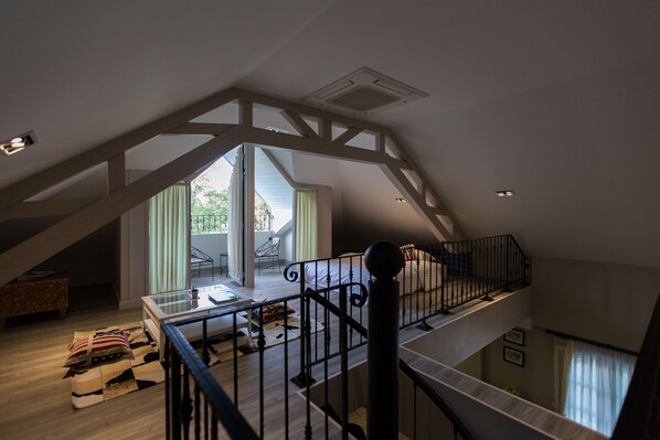 A spacious loft with a high ceiling, exposed wooden beams, a balcony, and a view of the outdoors. - Merchant House Chiangmai (Chiang Mai)