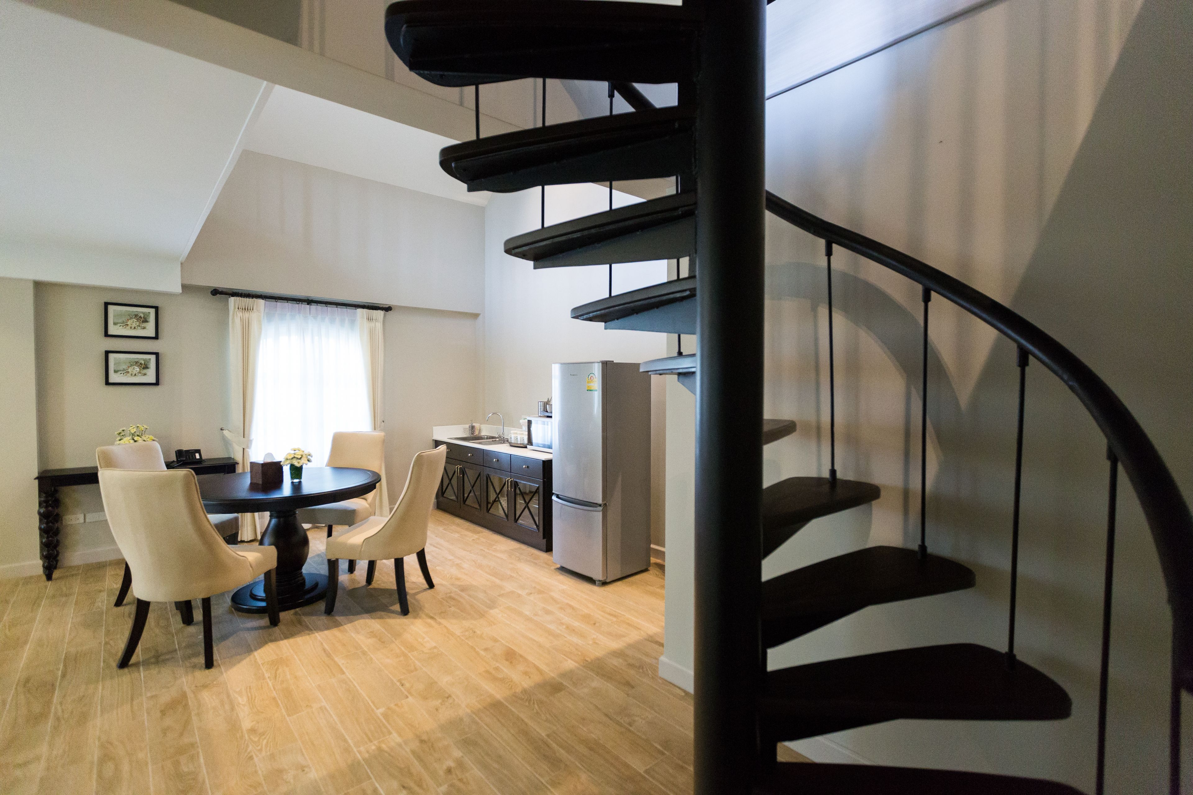 Una cocina moderna con comedor, una escalera en espiral y vistas al salón.
