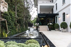 A hotel entrance with a water feature, potted plants, and a well-maintained outdoor area.