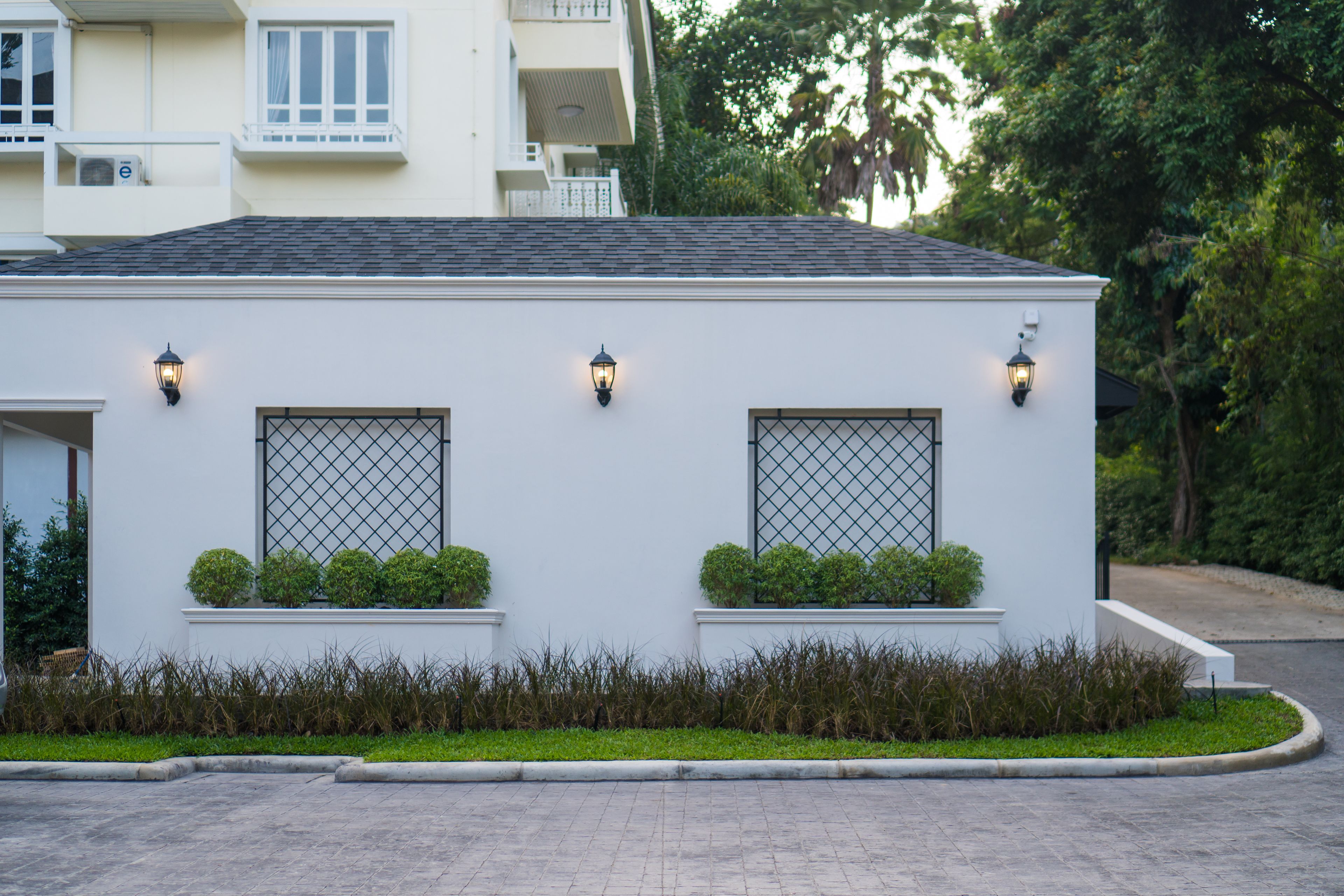 A modern building with two windows, each with a metal grid design, and two wall-mounted lights.