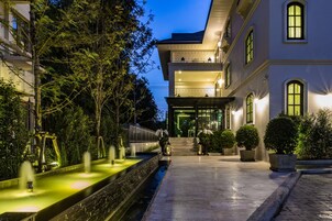 A modern building with a well-lit entrance, a water feature, and a paved pathway.