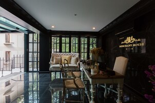 A spacious lobby with a high ceiling, a grand piano, and a seating area with a sofa and chairs.