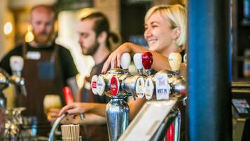 En bar med flera kranar och en person som häller upp en drink.