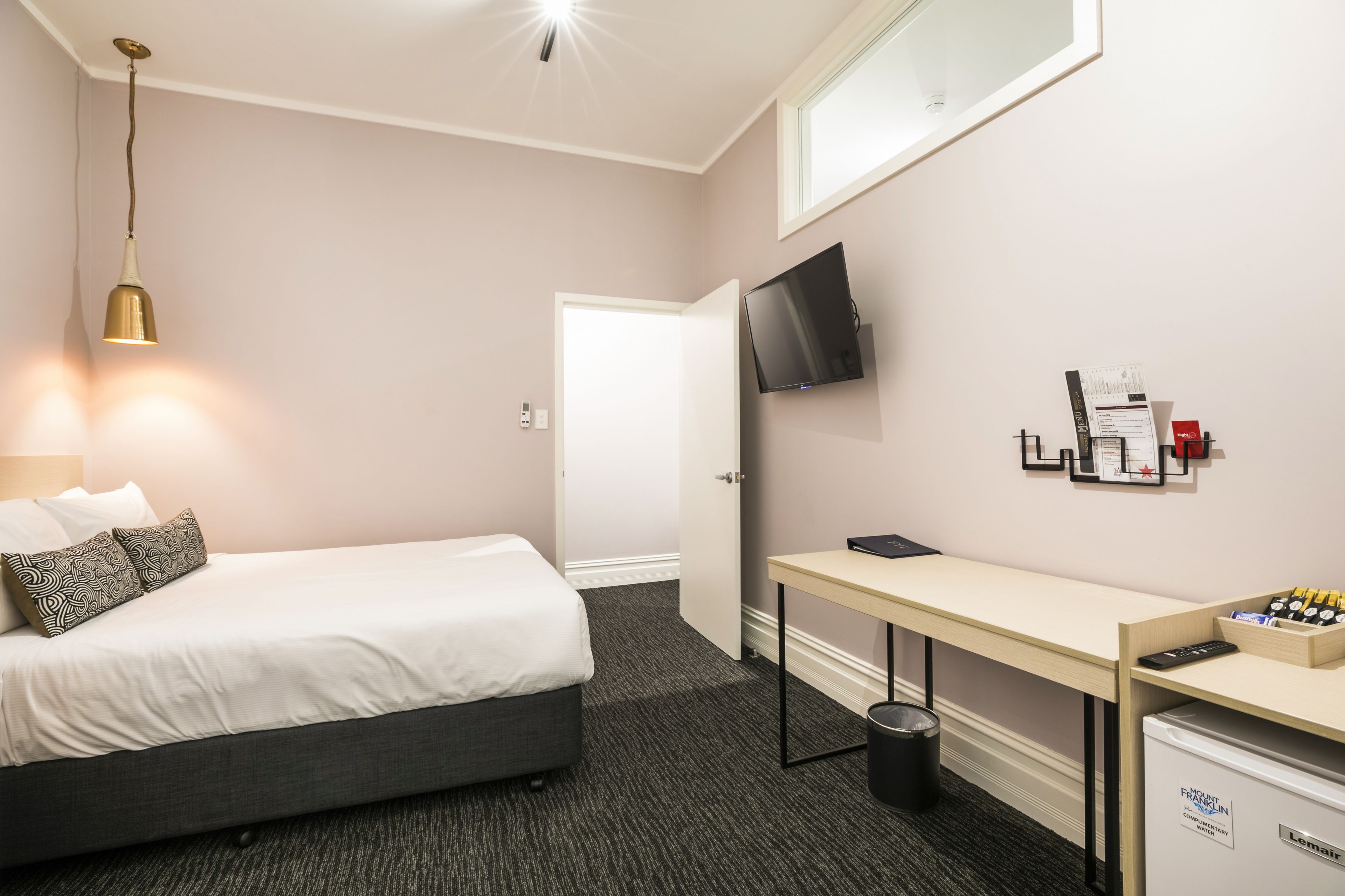 Una habitación de hotel con cama, escritorio y televisión.