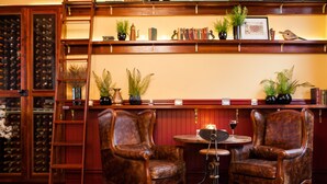 Una habitación con dos sillones de madera, una pequeña mesa redonda y una estantería con libros y objetos decorativos.
