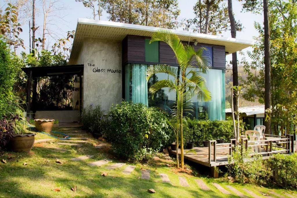 A modern house with a garden, a wooden deck, and a pathway leading to the entrance.