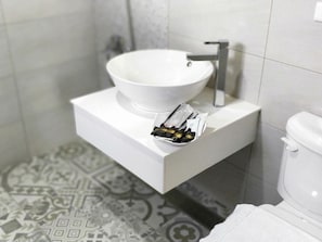 A bathroom with a white sink, a small tray with toiletries, and a toilet.