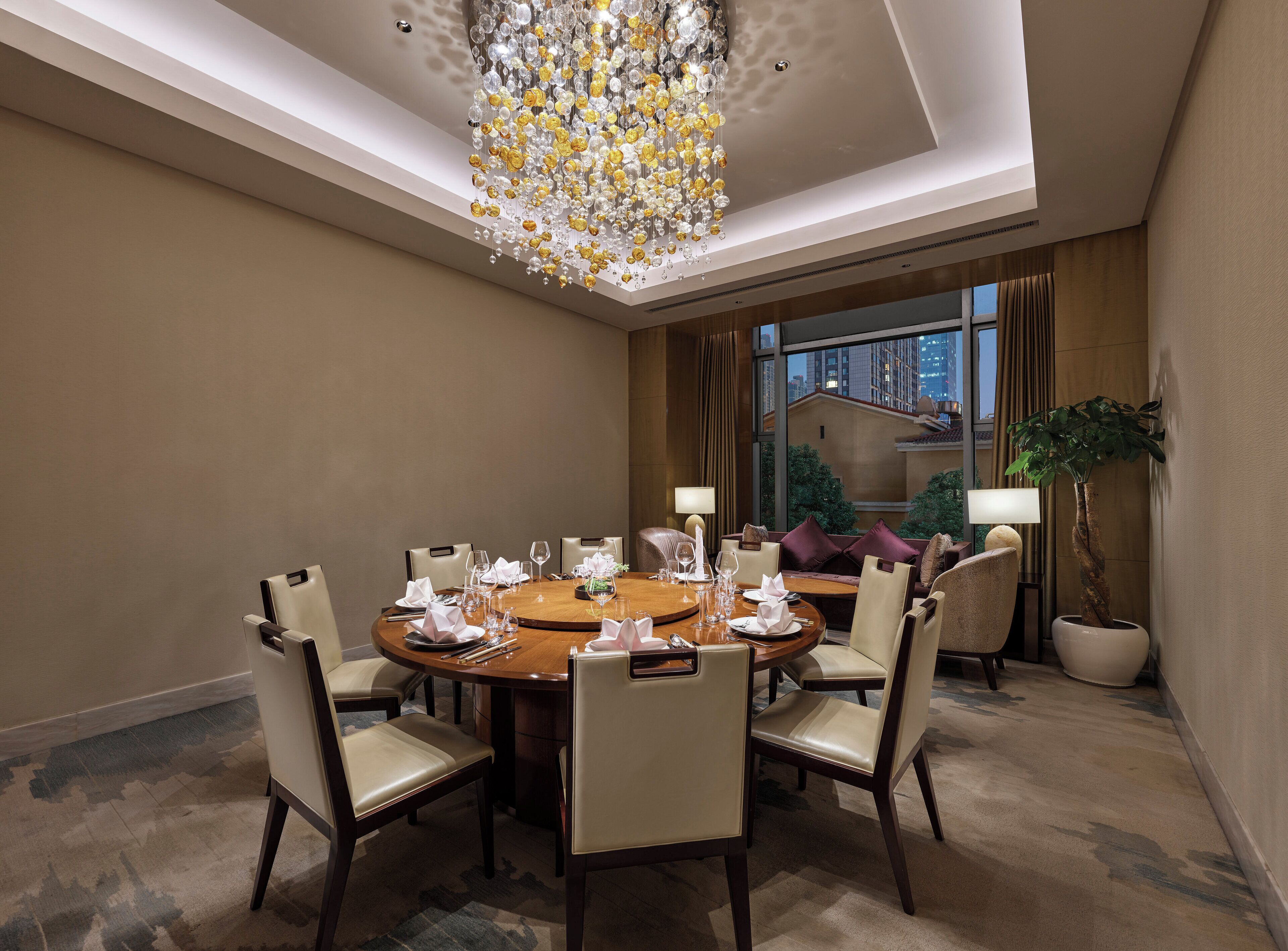 A hotel dining room with a round table set for six, surrounded by six chairs.