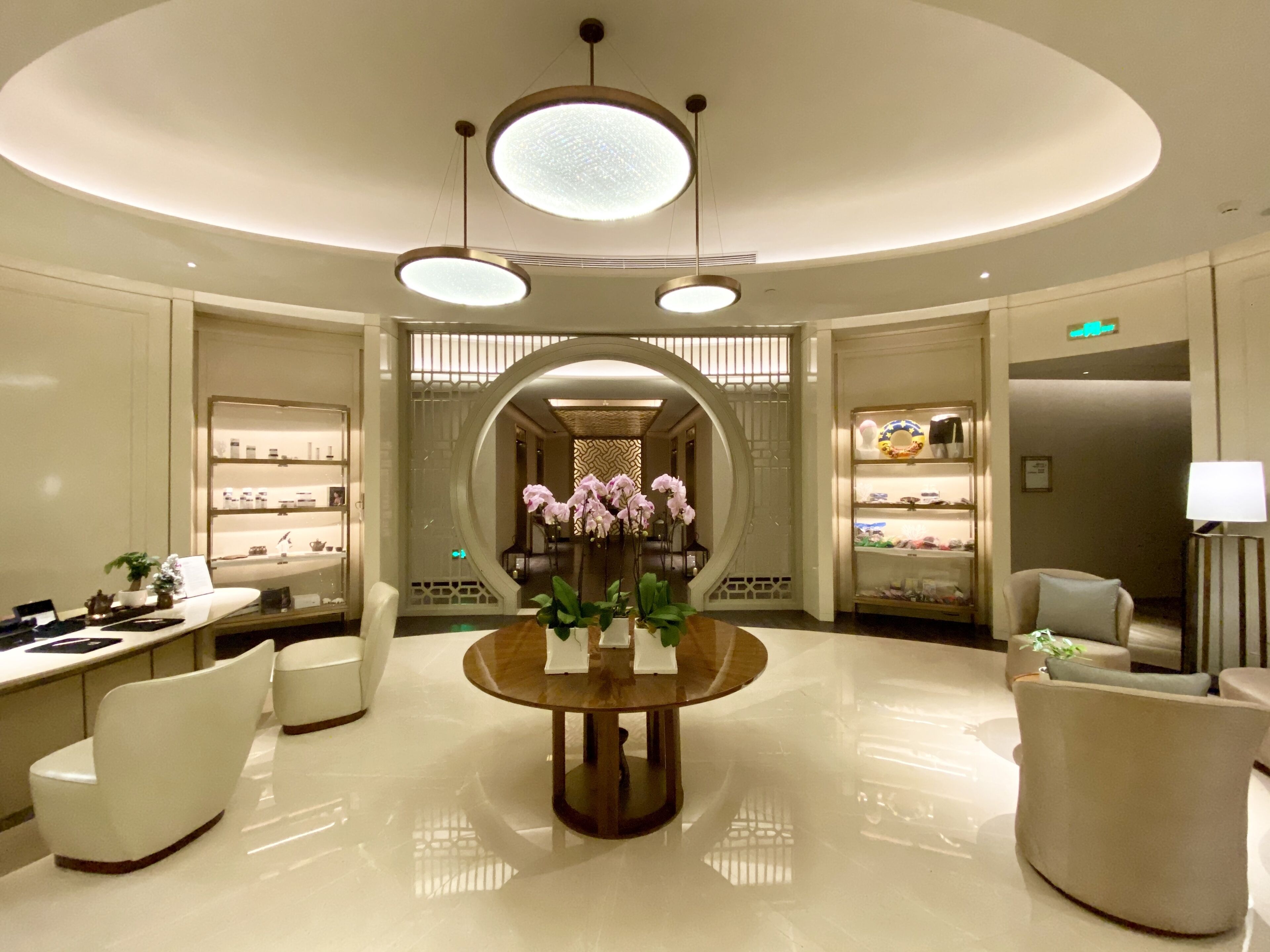 A modern lobby with a round table, white chairs, and a decorative archway.