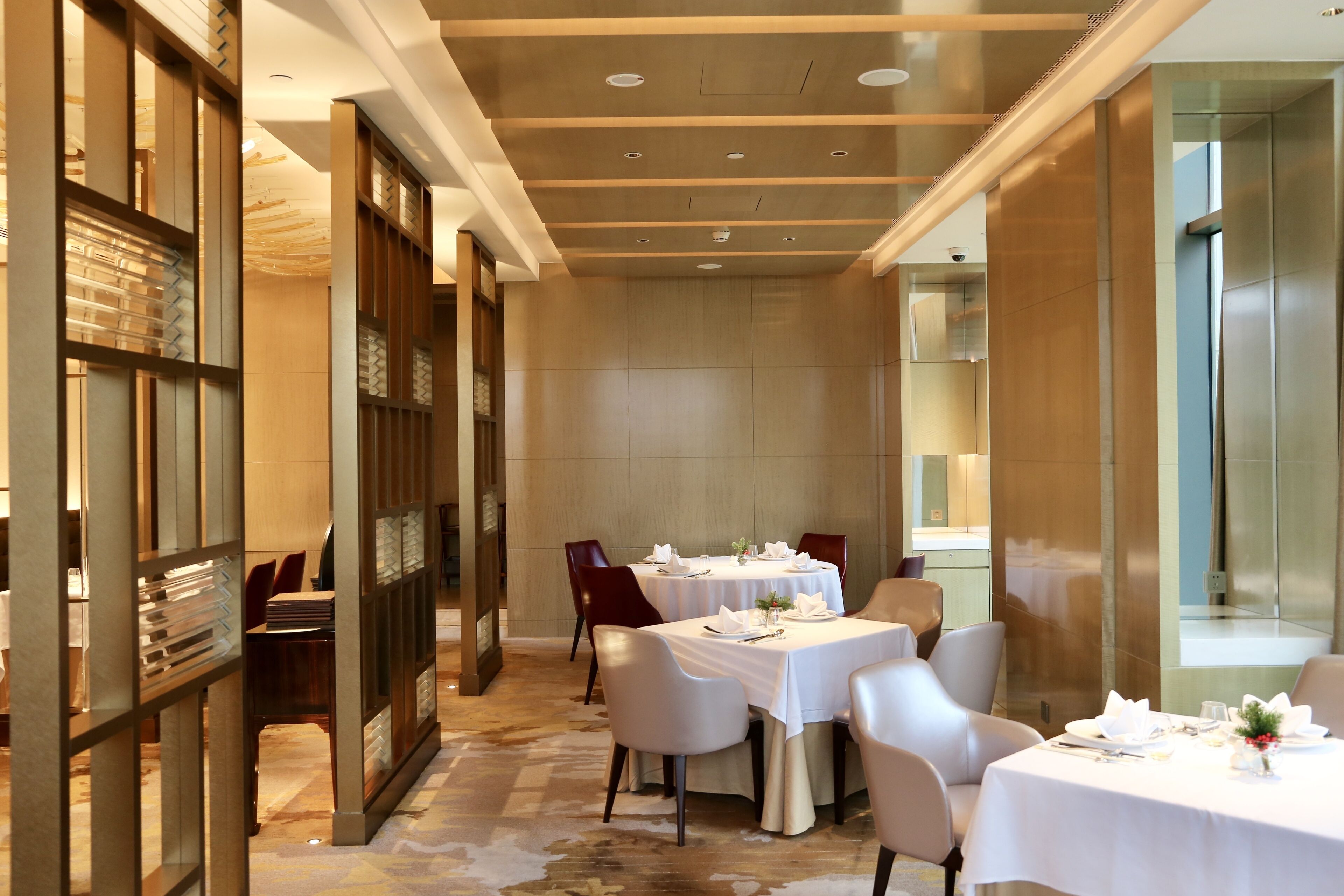 Un comedor moderno con varias mesas dispuestas para comer, con manteles blancos y sillas.