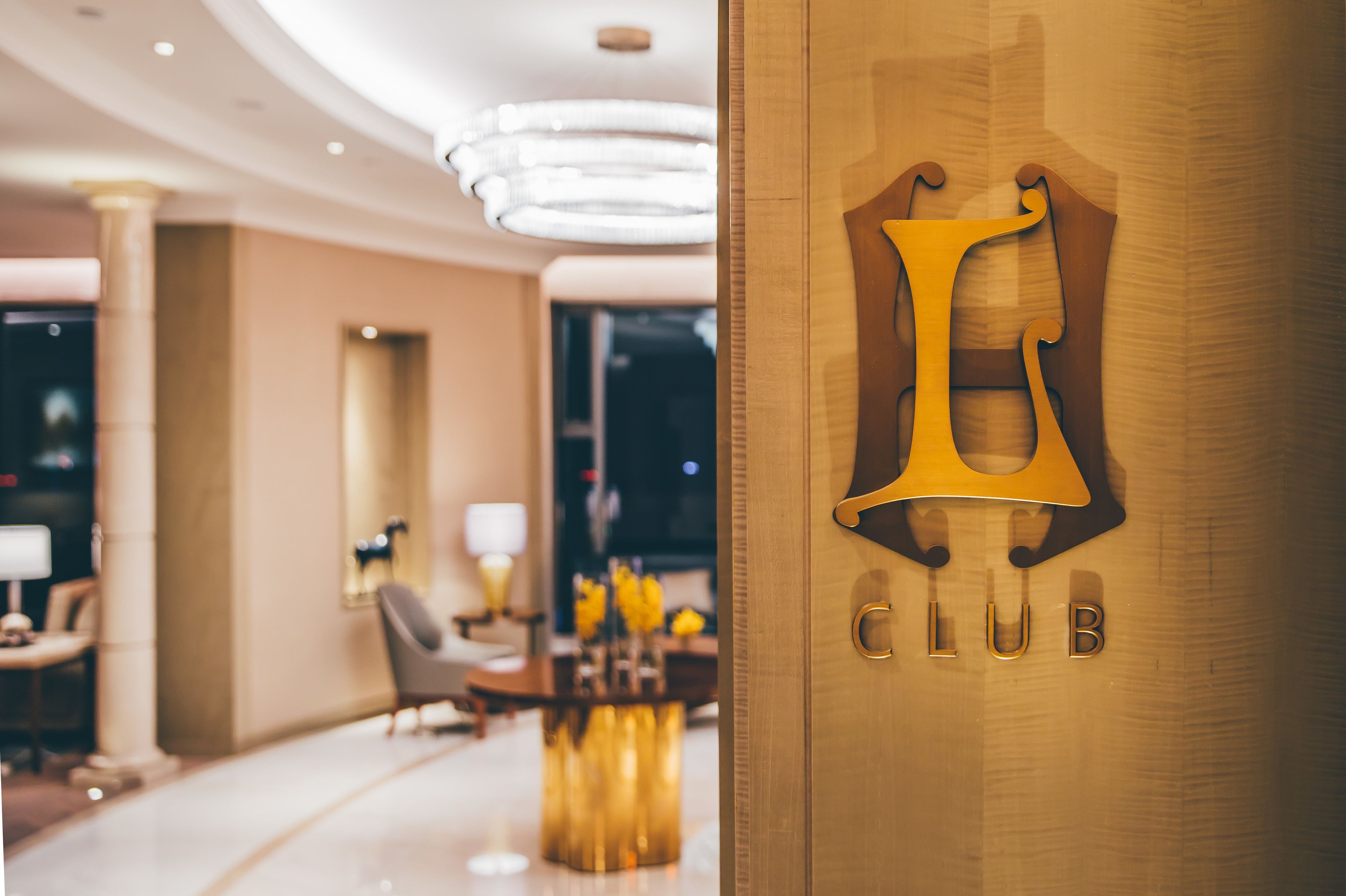 A modern hotel lobby with a prominent 'CLUB' sign on a wooden door.