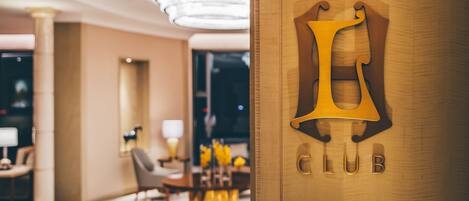 Un moderno vestíbulo de hotel con un letrero grande que dice 'CLUB' en una puerta de madera.