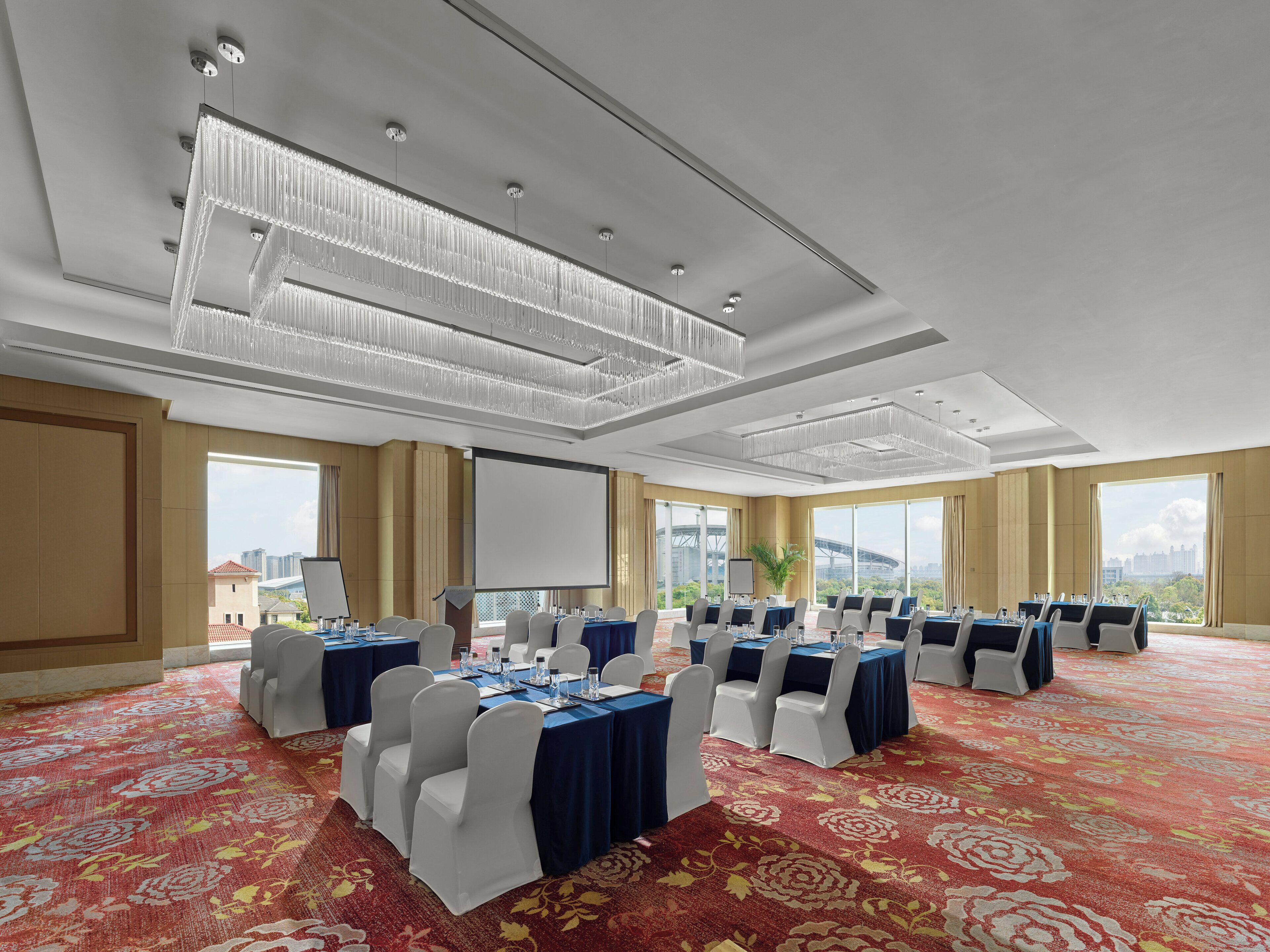 Un salón de conferencias con mesas dispuestas para reuniones, ventanas amplias y vistas a la ciudad.