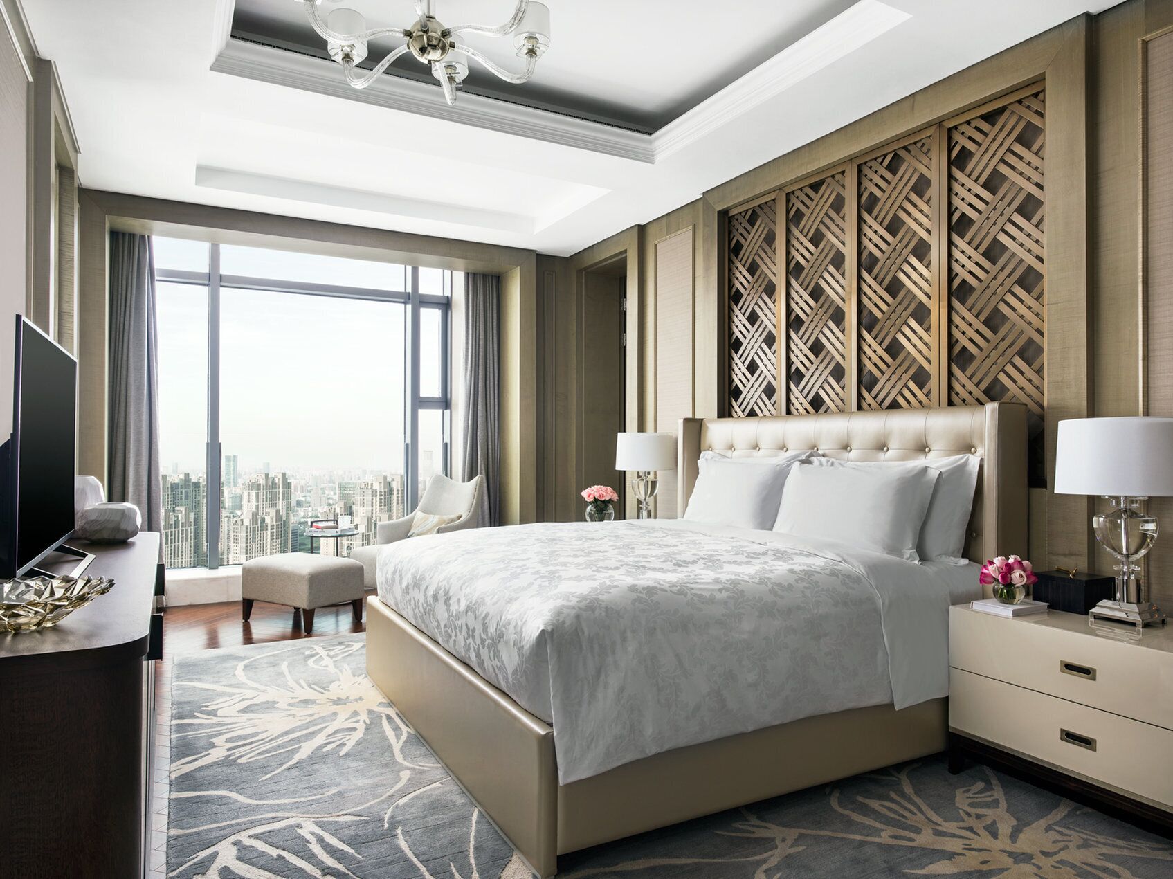 Habitación de hotel moderna con una cama grande, un escritorio con televisor y vistas a la ciudad.