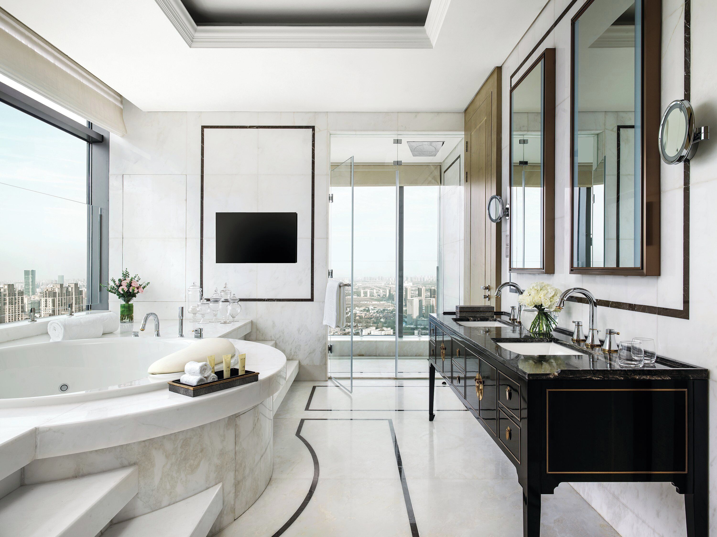 A modern bathroom with a large bathtub, a vanity with a black countertop, and a large mirror.