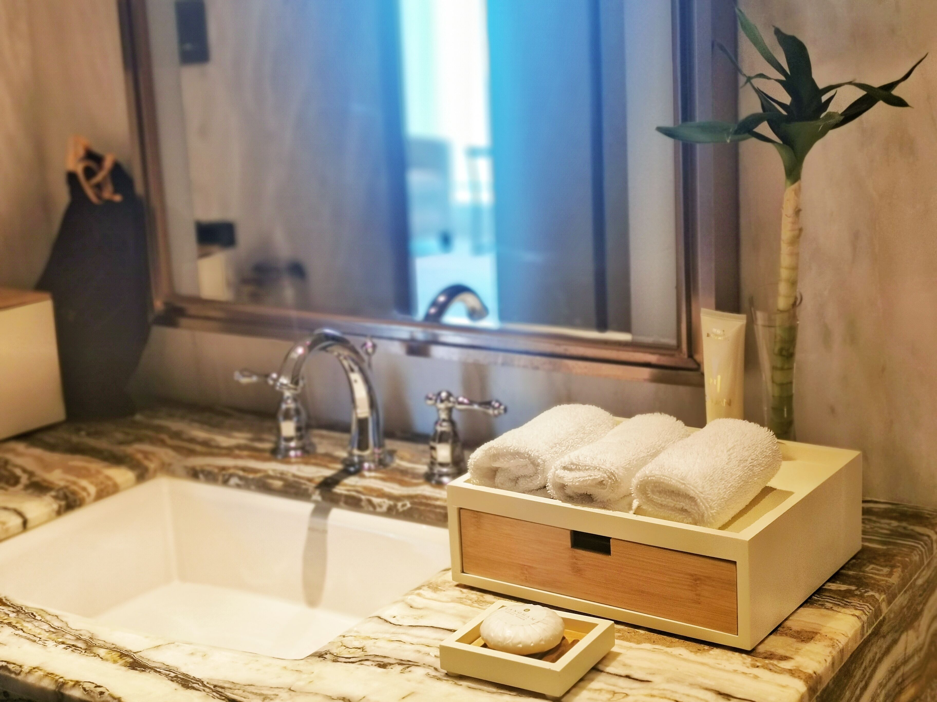 Un bany amb un taulell de marbre, un lavabo i un mirall. Hi ha tovalloles i un plat per al sabó al taulell.