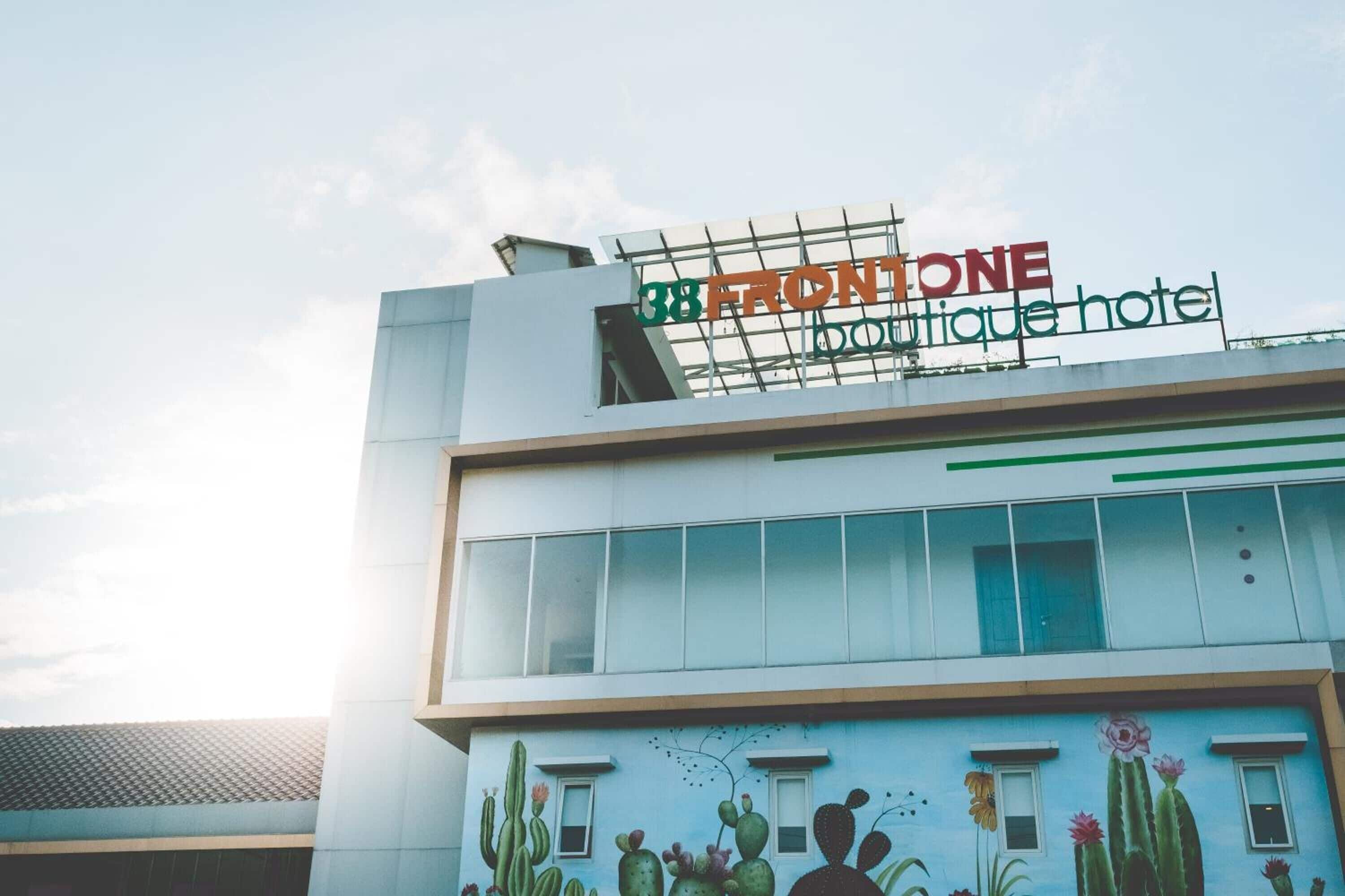 A building with a sign reading "38 FRONTONE Boutique hotel" and a mural of cacti and flowers on the facade.