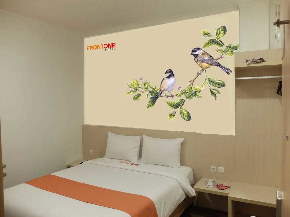 A hotel room with a bed, a nightstand, and a wall with a bird mural.